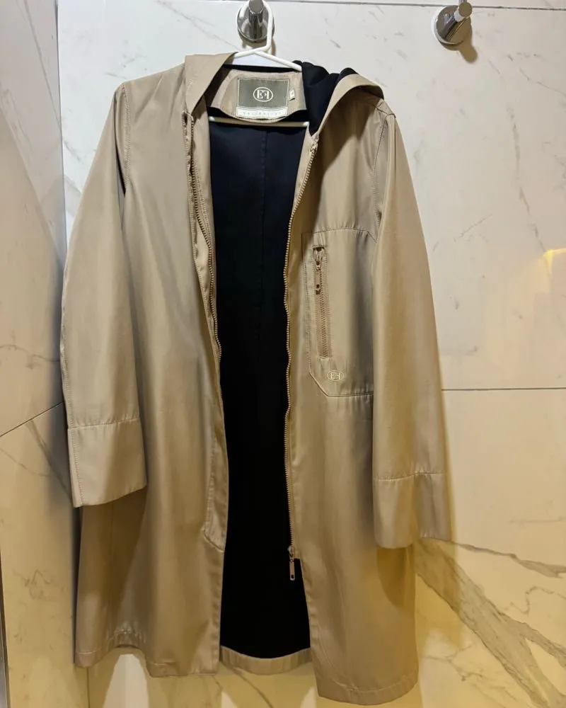 Impermeable largo con capucha, ideal para días de lluvia o para completar un look casual. Su diseño moderno y funcional lo convierte en un básico indispensable para entretiempo.