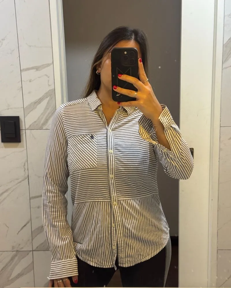 Camisa de rayas blancas y azules, manga larga, con bolsillos en el frente. Ideal para un look casual y cómodo.