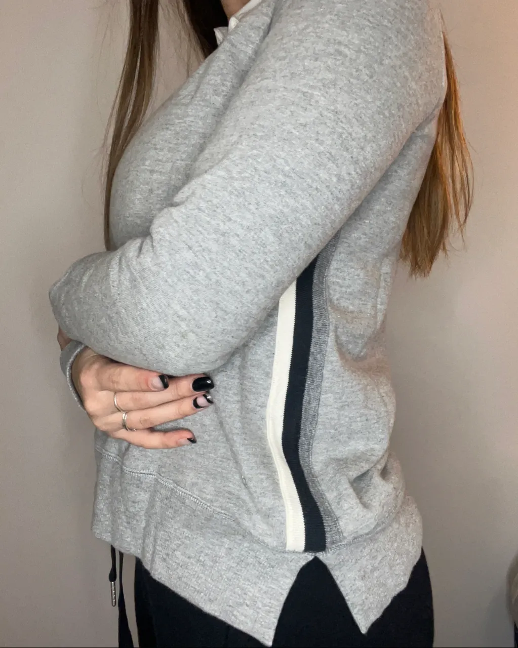 Remera gris de manga larga con cuello redondo y detalle de franjas verticales blancas y negras en los laterales. Posee un cuello de camisa blanco incorporado.