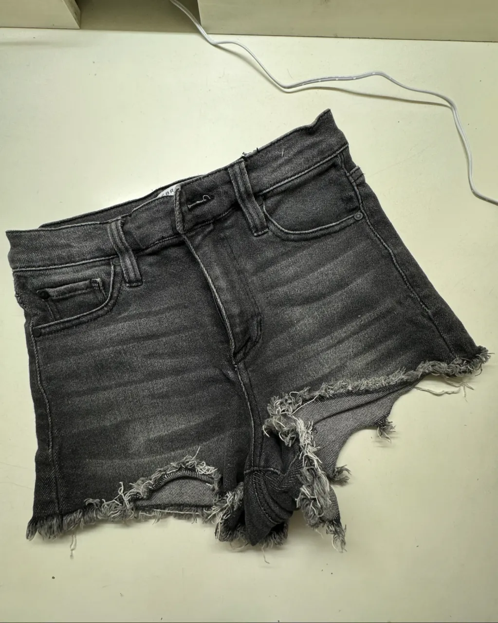 Shorts de jean negros con roturas y detalles deshilachados en los bordes.