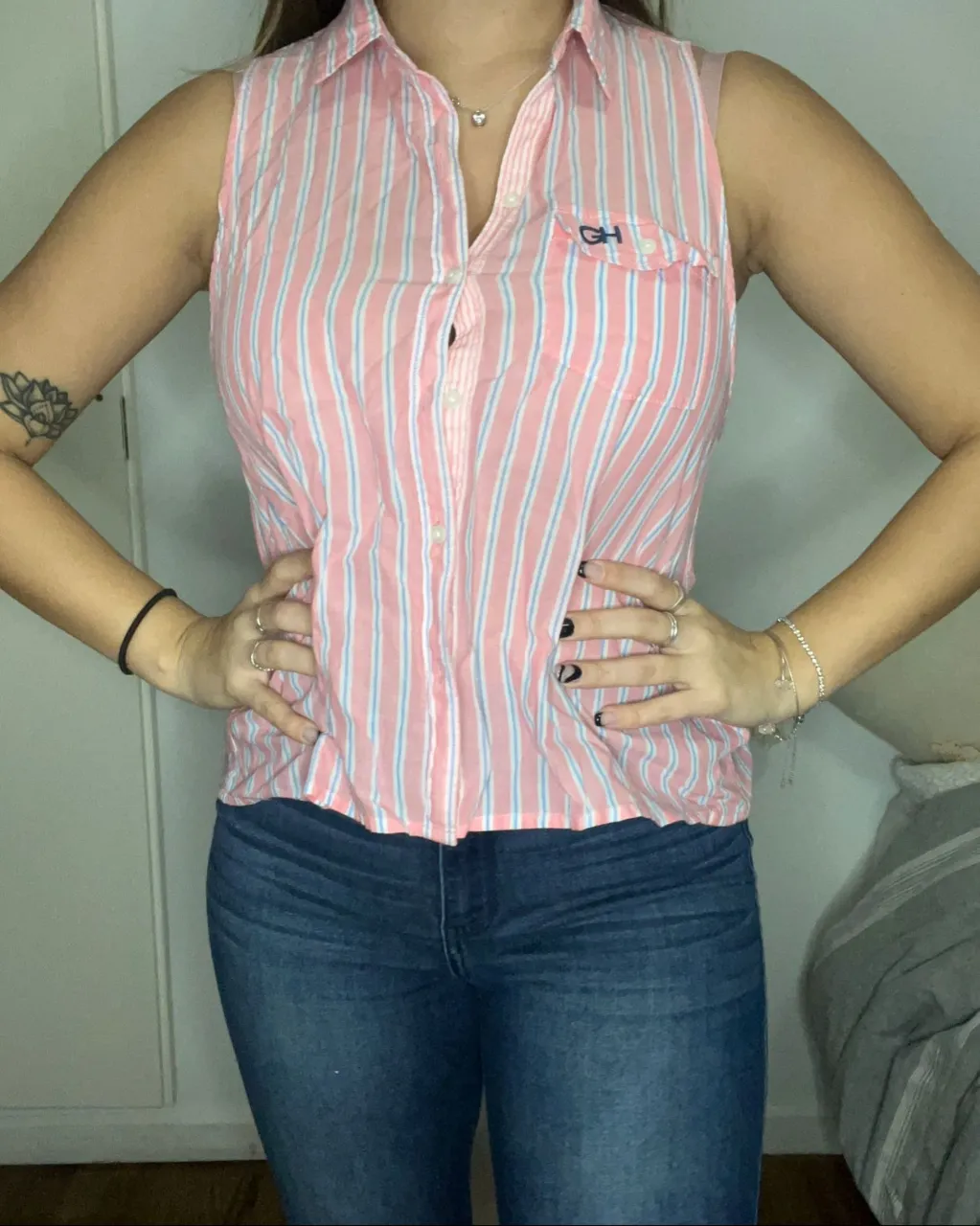 Remera a rayas verticales rosas y celestes, sin mangas y con cuello de camisa. Posee botones al frente y un bolsillo en el pecho izquierdo con un logo bordado.