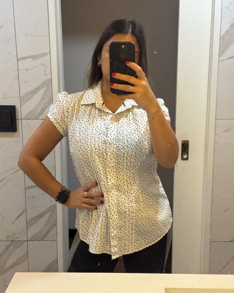 Camisa blanca de manga corta con estampa de lunares negros. Cuello camisero y botones al frente. Ideal para un look casual y canchero.