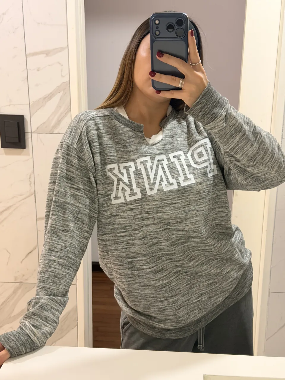 Remera gris melange con estampa "PINK" en blanco en el frente. Cuello redondo con tajos laterales.