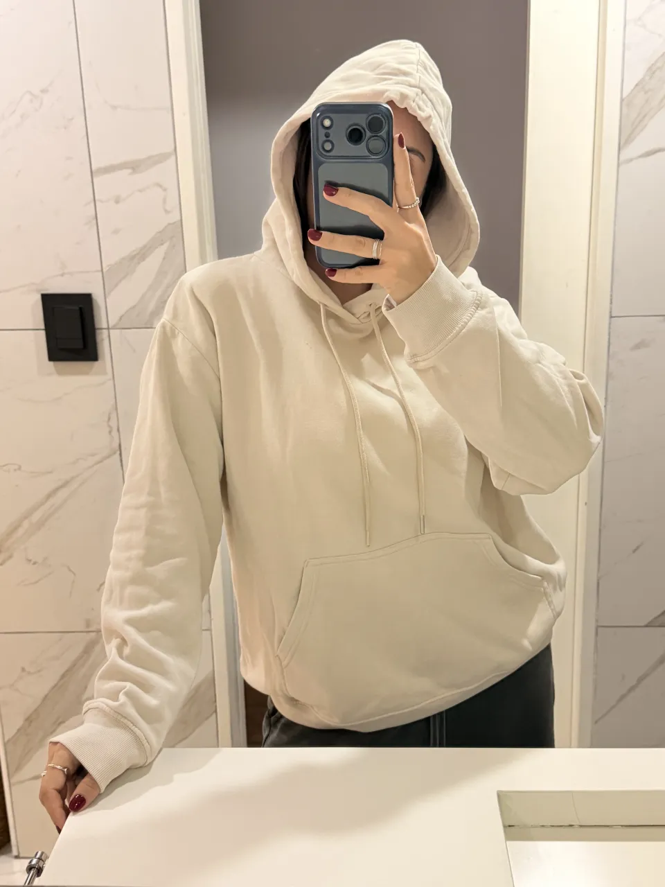 Buzo con capucha de color crudo y bolsillo canguro al frente. Cordones en la capucha.