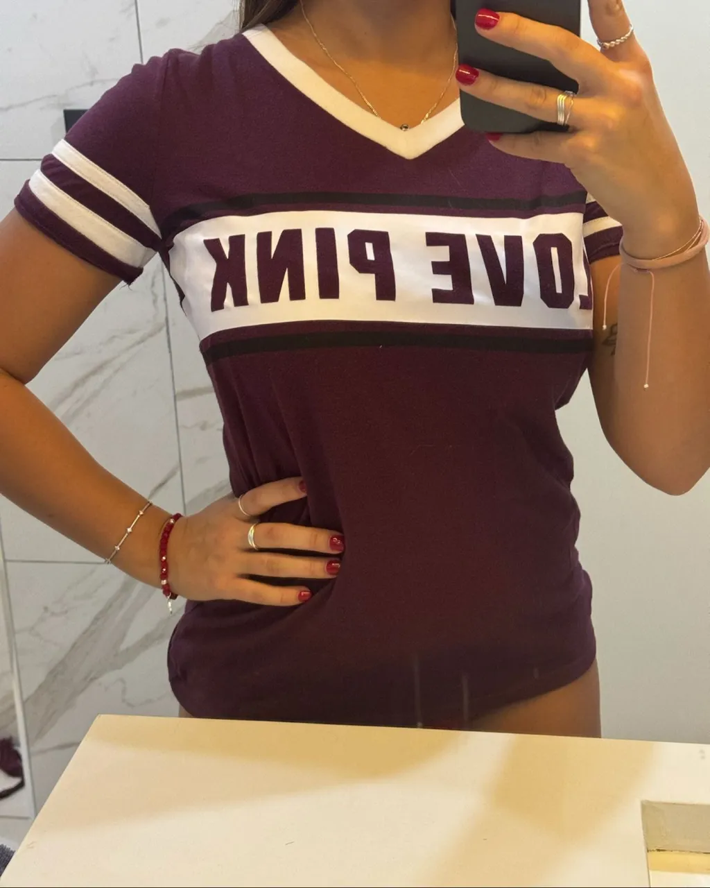 Remera manga corta de algodón y poliéster con cuello en V y estampa "LOVE PINK" en el frente. Posee detalles de franjas blancas en las mangas.