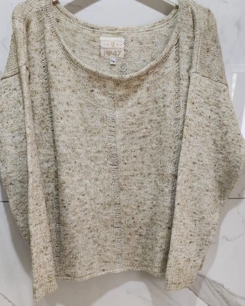 Sweater de tejido rústico con cuello redondo y mangas largas. Presenta detalles de costuras verticales en el frente y en las mangas.