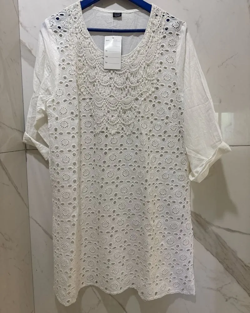 Blusa blanca de algodón con detalles de crochet y bordados. Manga corta y escote redondo. Perfecta para un look fresco y bohemio en días de sol.