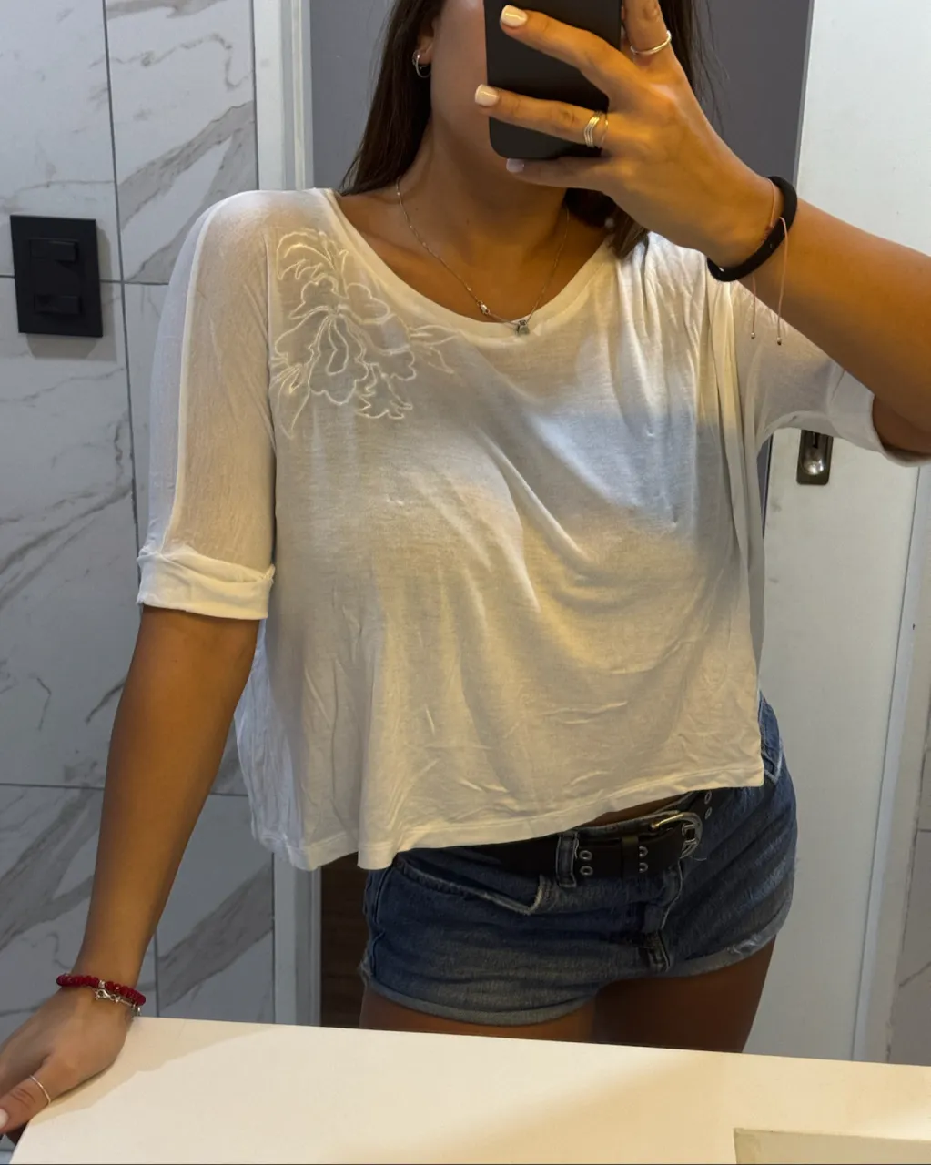 Remera blanca de manga corta con un bordado floral en la parte delantera superior. Cuello redondo.