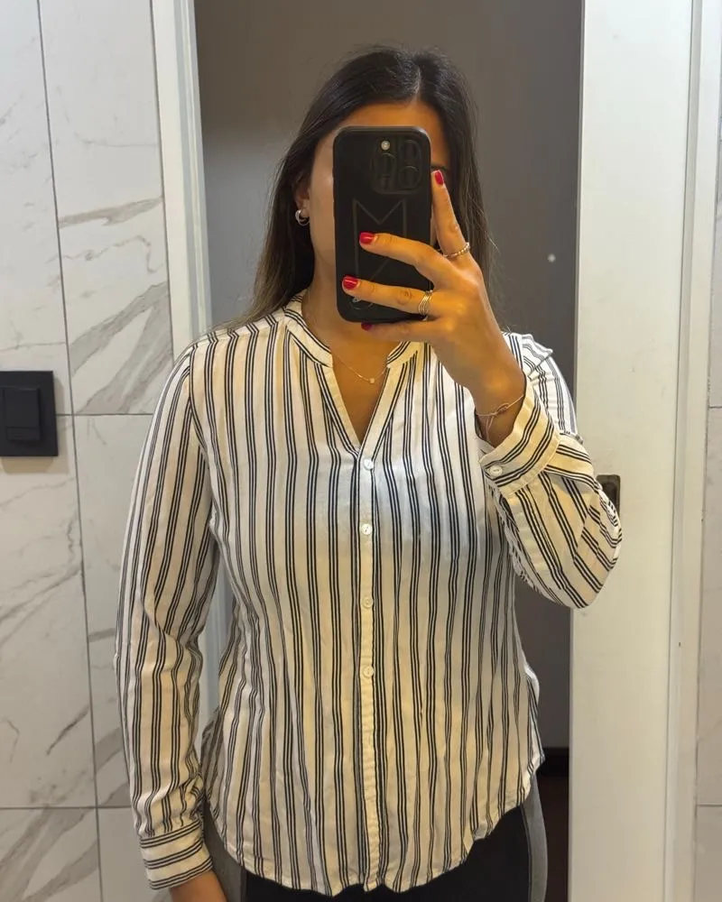 Camisa a rayas blanca y negra, manga larga, con cuello mao y botones al frente. Ideal para un look casual o de trabajo.