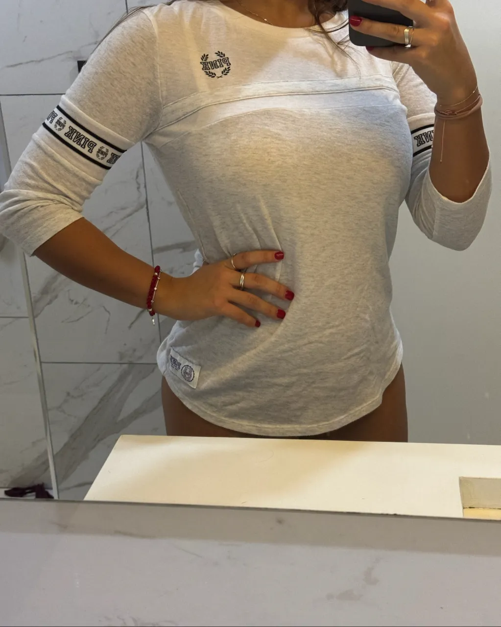 Remera manga larga gris con detalles de franjas negras y blancas en las mangas. Posee logo de la marca bordado en el frente.