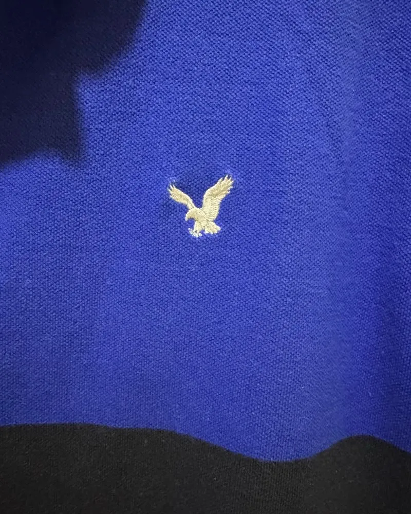 Remera polo azul y negra con bordado de águila. Ideal para un look casual y moderno.