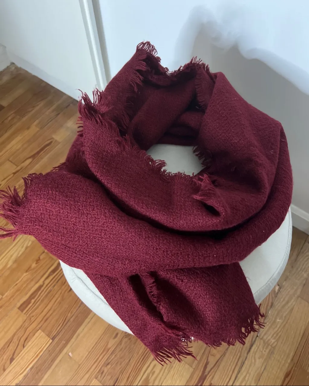 Bufanda tejida de color bordó con flecos en los bordes.