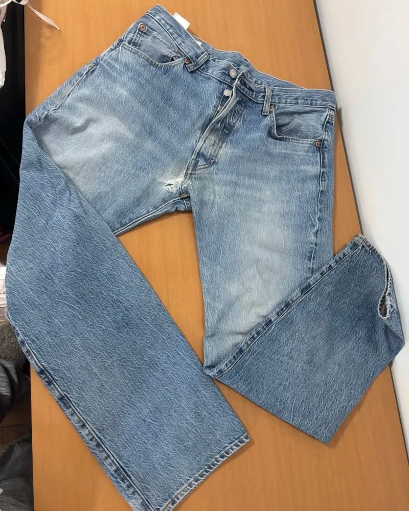 Jeans Levi's 501 vintage, tiro alto, corte recto y color azul claro. Tienen un detalle de rotura en la zona de la bragueta y desgaste clásico de uso. Perfectos para un look casual y canchero.
