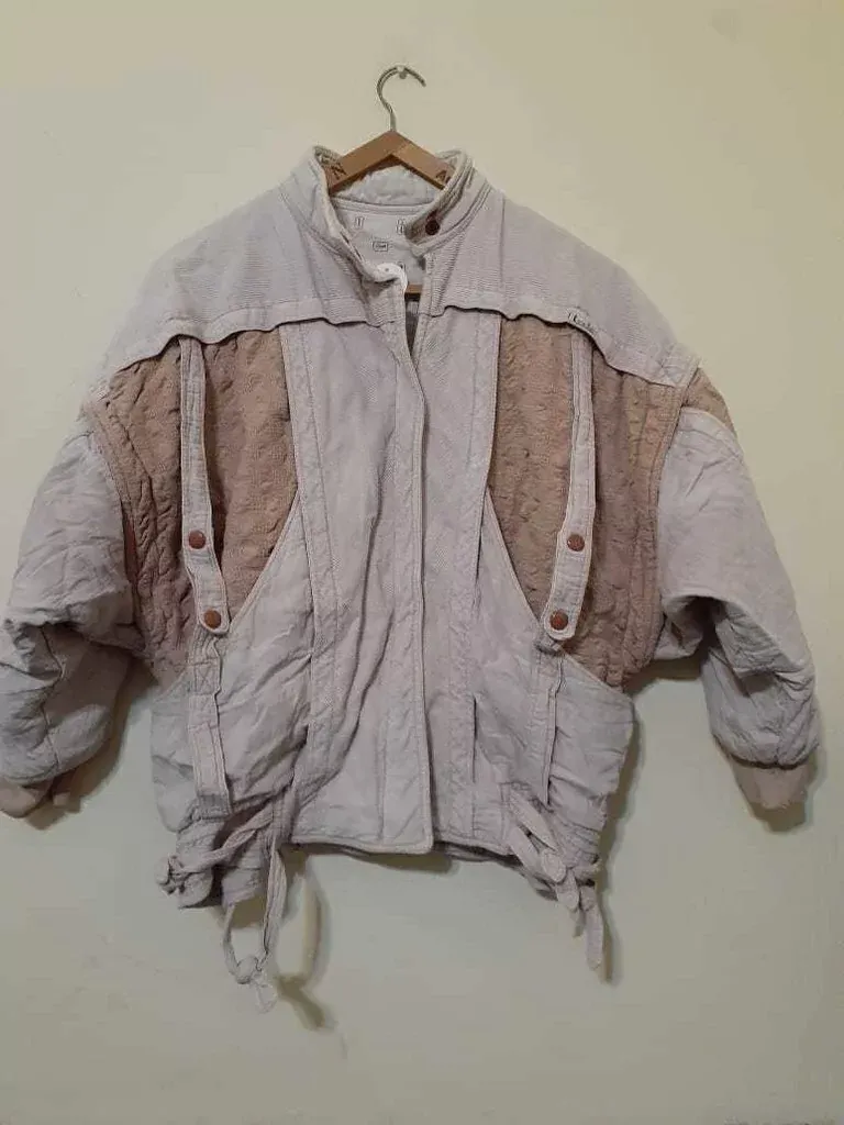 Campera de abrigo con recortes texturizados en mangas y frente. Cierre central y botones a presión. Mangas anchas 