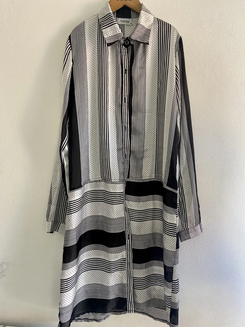 Camisa larga estampada con rayas verticales y horizontales. Posee cuello camisero y botones al frente.