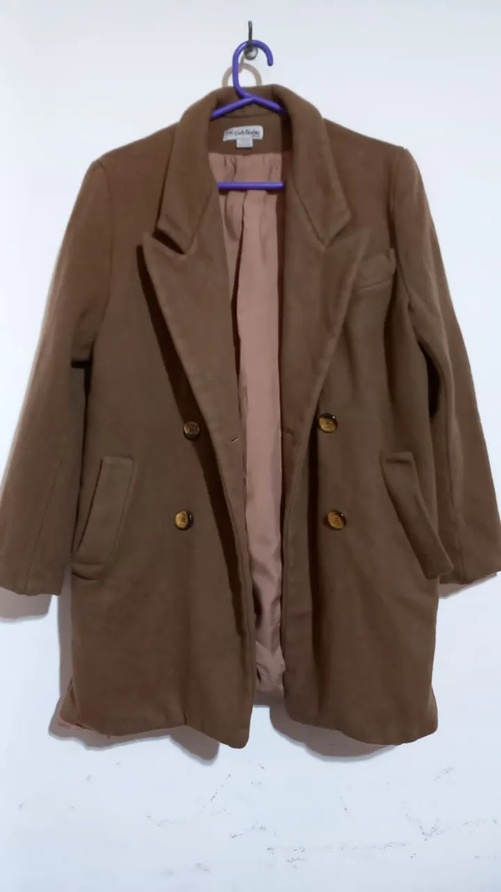 Tapado de paño color marrón. Posee cuello solapa, doble abotonadura y bolsillos frontales.