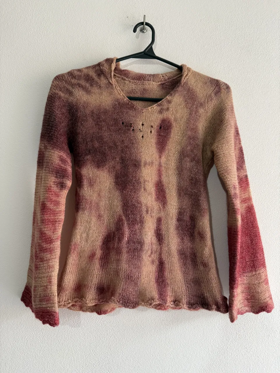 Sweater tejido con tipo vincha. Posee un estampado tie-dye en tonos tierra y bordó. El cuello es redondo y tiene mangas largas acampanadas con terminación desflecada. 