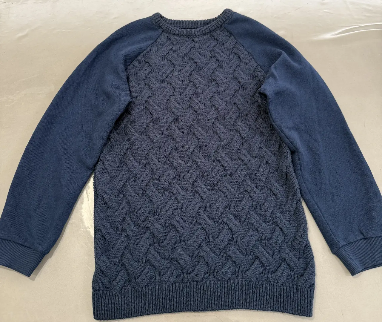 Sweater de tejido grueso con diseño en relieve en el frente. Cuello redondo y mangas en color liso. Ideal para un look casual y abrigado.