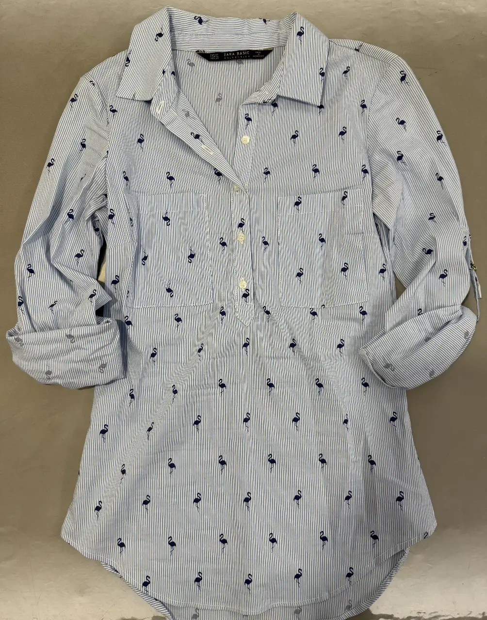 Camisa de mujer Zara Basic con estampado de flamencos, a rayas celestes y blancas. Manga larga con detalle para arremangar. Ideal para un look casual y fresco.