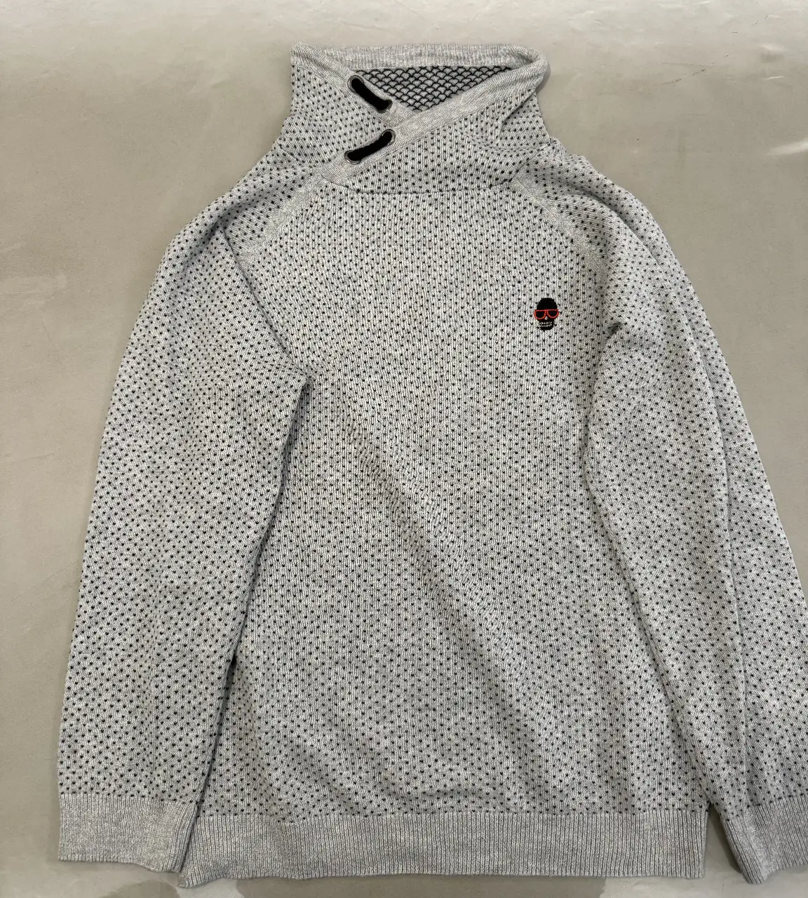 Sweater de cuello alto para niño, de la marca Zara. Confeccionado en un tejido de punto gris con detalles en negro. Tiene un pequeño logo en el pecho y un diseño moderno y abrigado, ideal para el invierno.