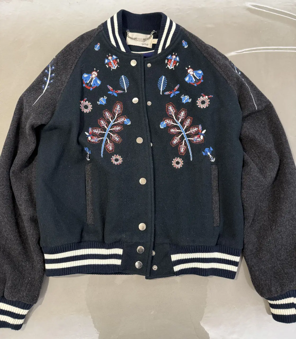 Campera bomber negra con detalles bordados y mangas grises. Ideal para un look casual y canchero.