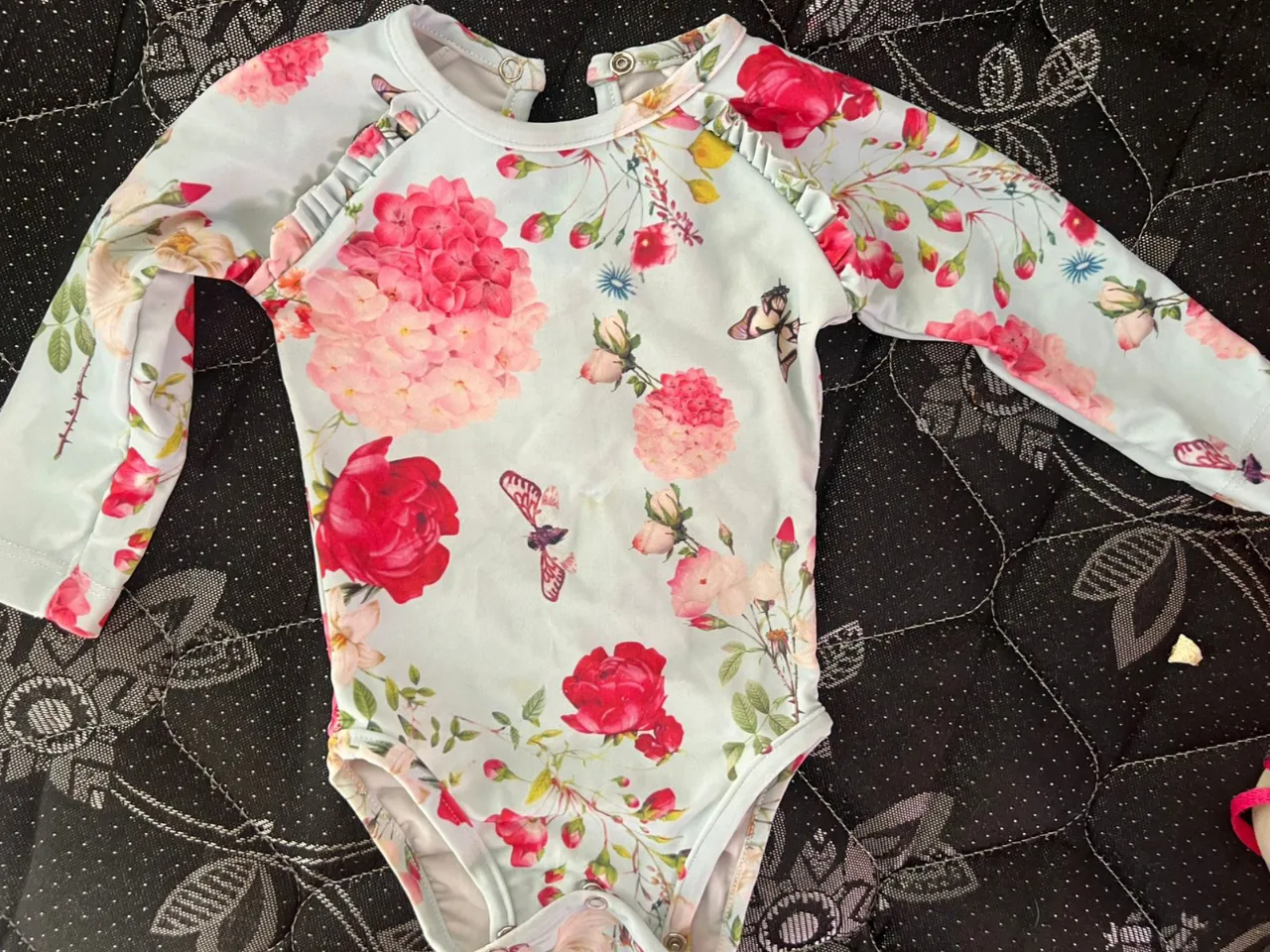 Body de manga larga para bebé niña, con un hermoso estampado floral en tonos pastel y mariposas. Ideal para el día a día o para una ocasión especial.
