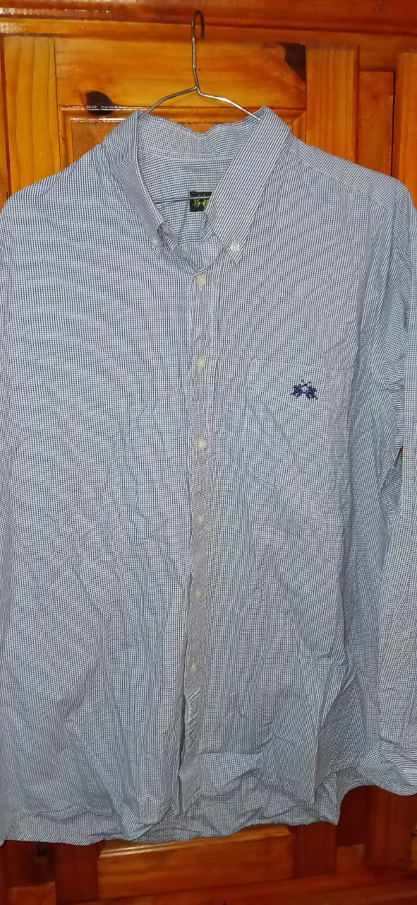 Camisa de hombre a cuadros en tonos azules y blancos, de manga larga. Ideal para un look casual y cómodo. Con logo bordado en el pecho y etiqueta de la marca visible.