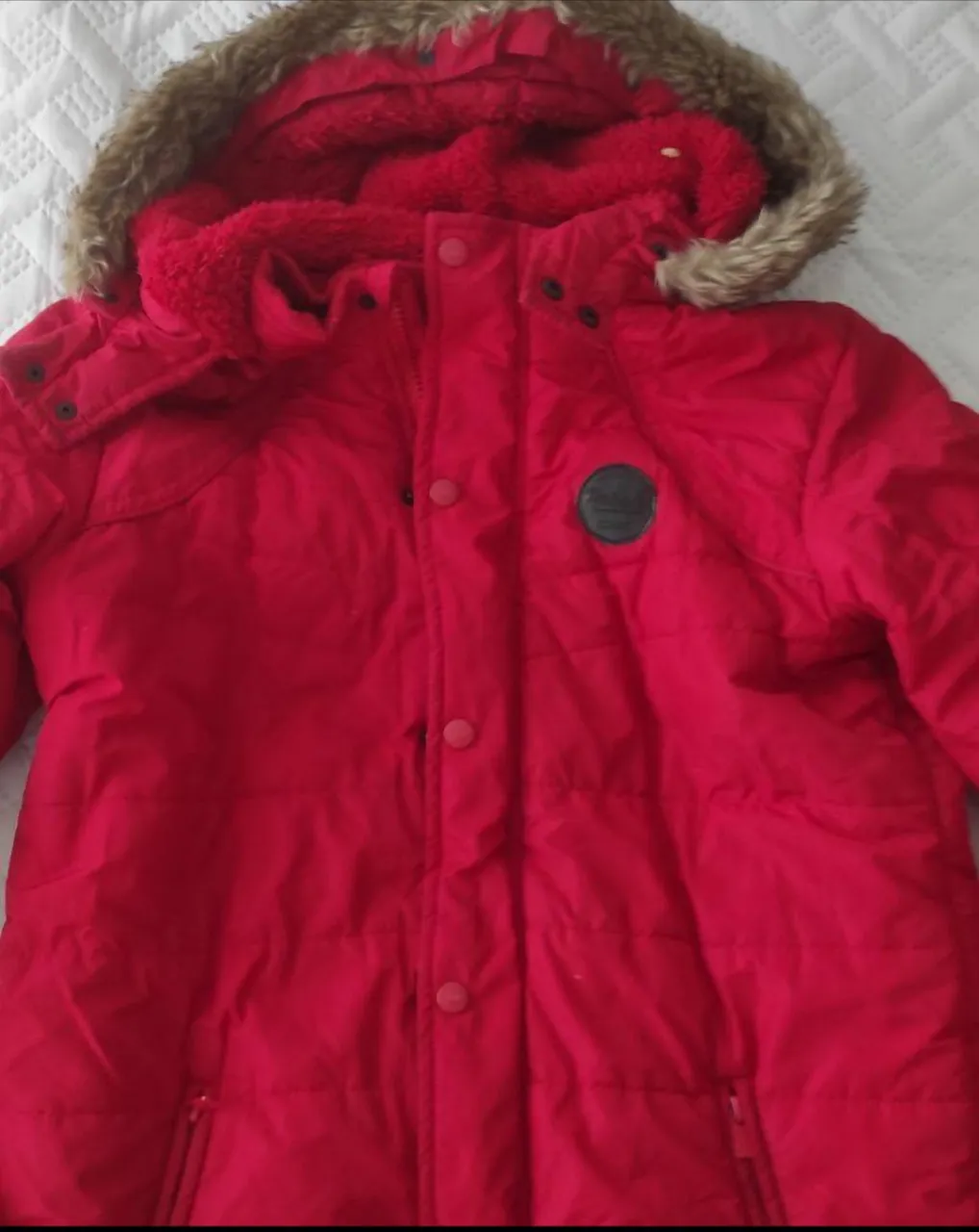 Campera roja acolchada con capucha de piel sintética. Ideal para el invierno, con cierre y botones.