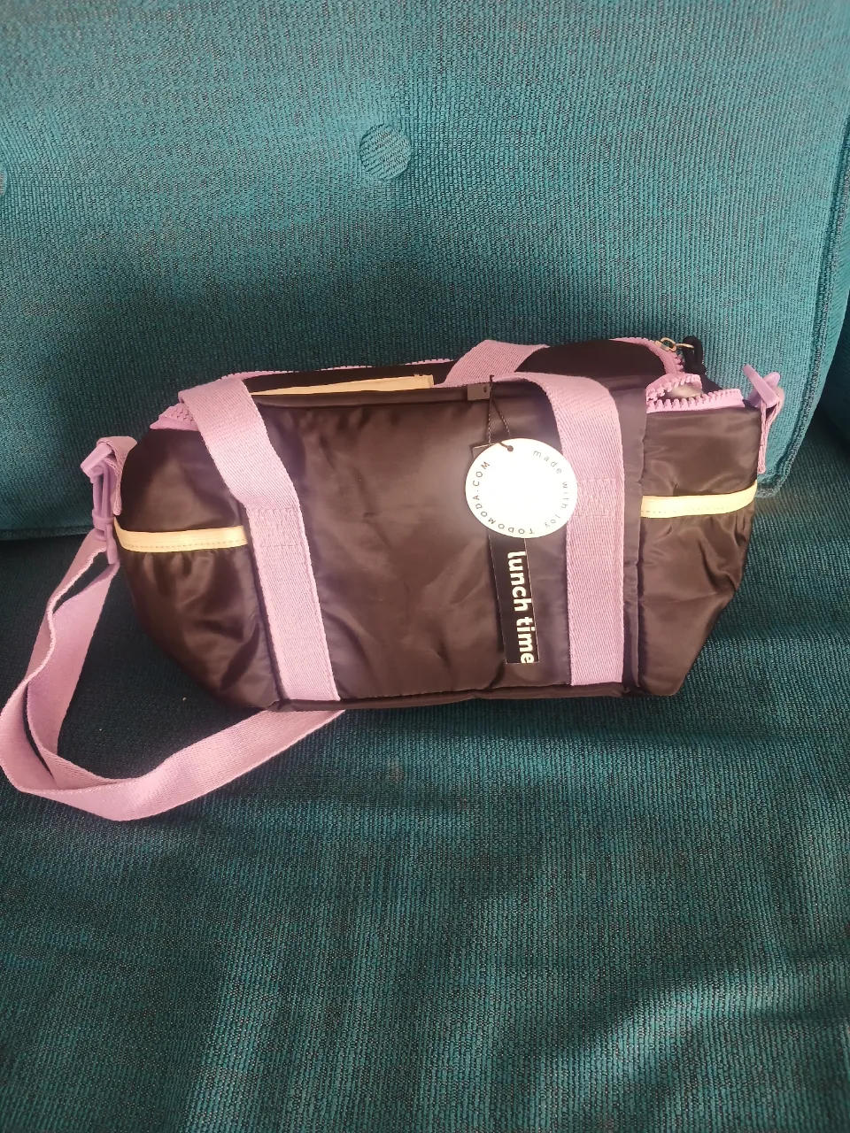 Lunchera, color negro con detalles en lila y amarillo. Ideal para llevar tus comidas con estilo. Marca Todo Moda.