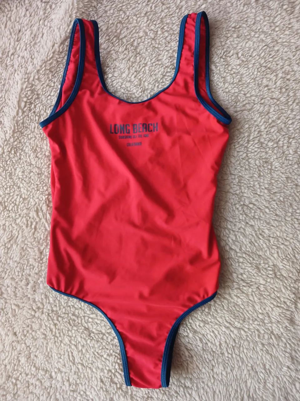 Traje de baño enterizo rojo con detalles en azul. Estampado "LONG BEACH" en el frente. Ideal para la playa o pileta.