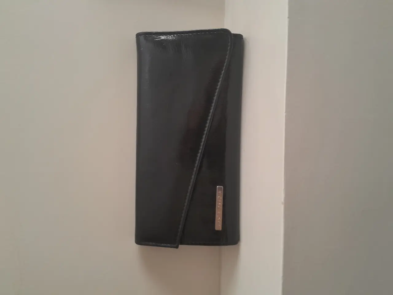 Cartera Jacob negra de cuero con hebillas y detalles metálicos. Ideal para un look moderno y sofisticado.