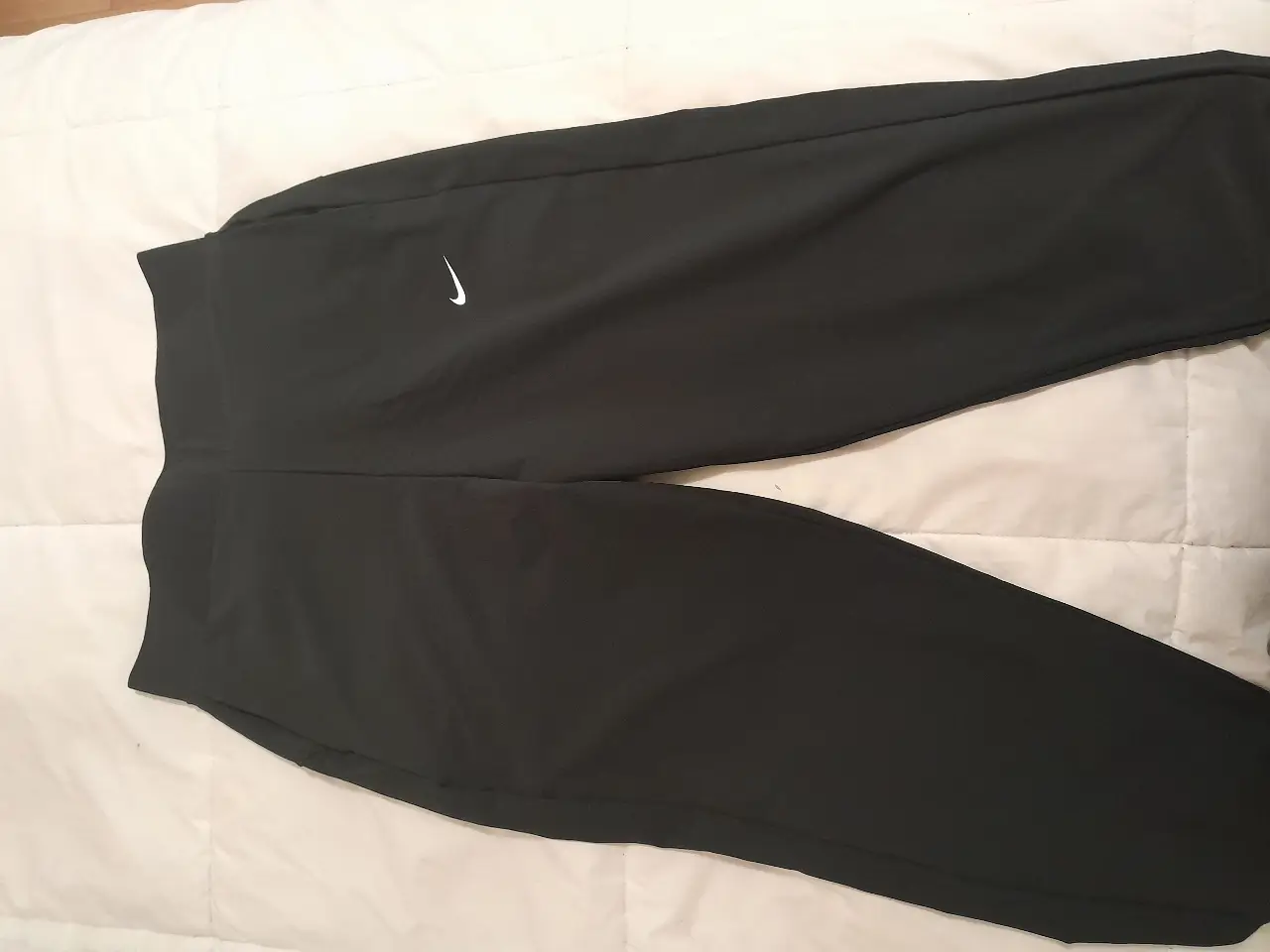 Pantalón deportivo negro de hombre, con logo de la marca Nike en blanco. Ideal para entrenar o para un look casual y cómodo.