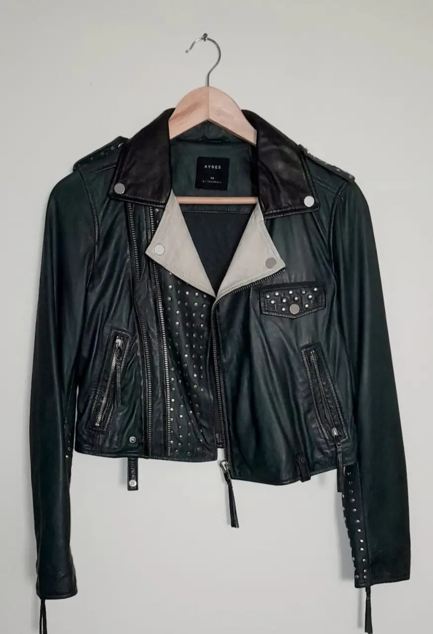 Campera de cuero estilo biker para mujer, color verde oscuro con detalles en negro. Diseño con tachas plateadas y cierre asimétrico. Ideal para un look rocker y moderno.