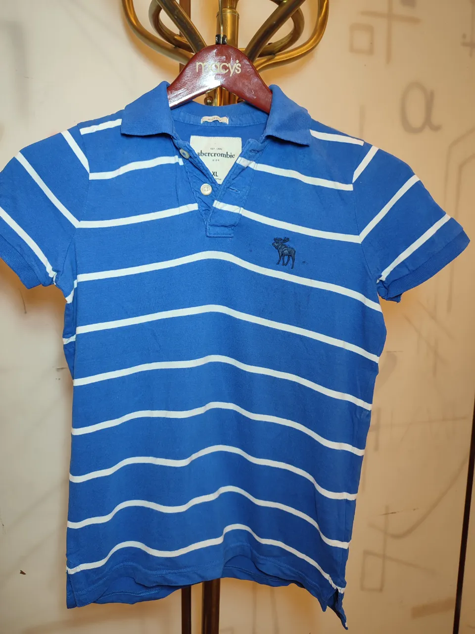 Remera polo a rayas azules y blancas. Tiene cuello y botones en la parte superior. Logo de la marca bordado en el pecho.largo 0,62.Ancho de hombros 0,38 Ancho de sisa 0,48