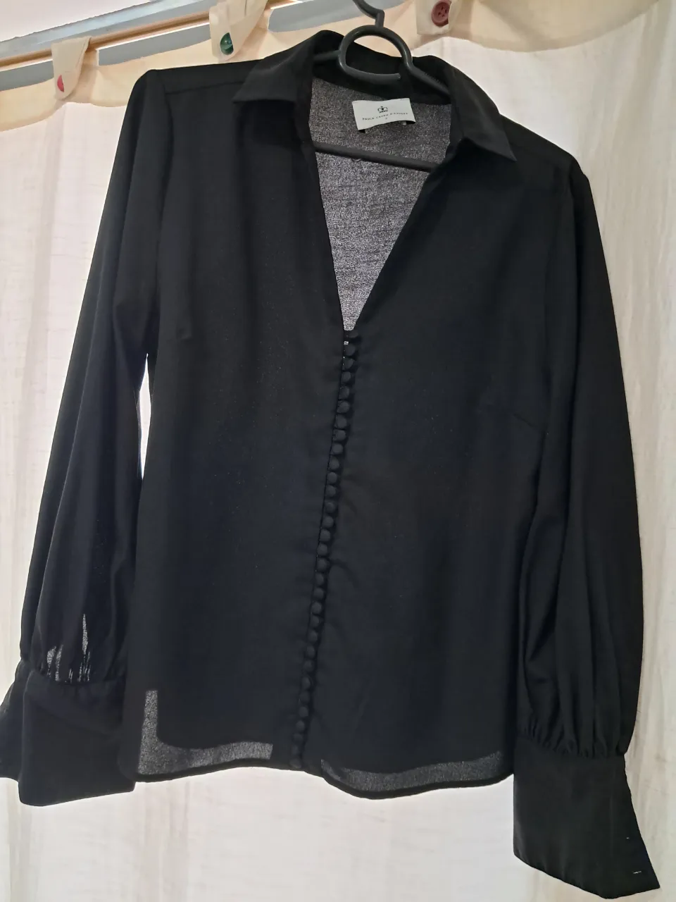 Camisa negra de vestir con botones al frente y mangas largas con puño. Elegante y versátil, ideal para un look sofisticado.