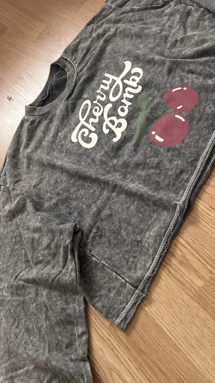 Buzo gris con estampa de cerezas y la inscripción "Cherry Bombs".