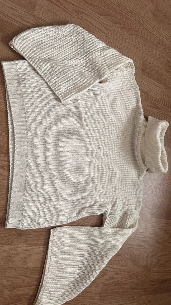 Sweater de tejido de punto color blanco roto con cuello alto.