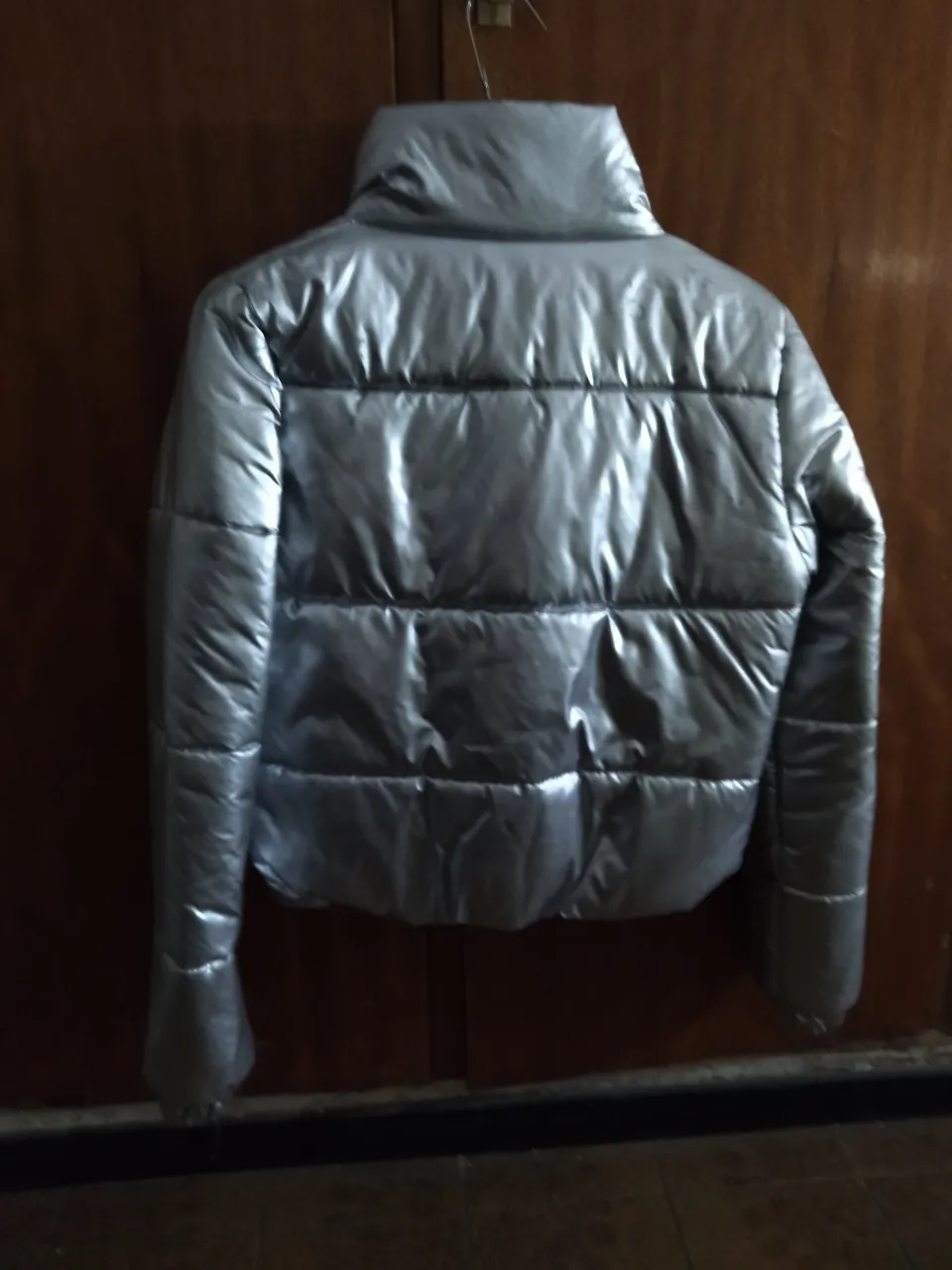 Campera acolchada plateada con cuello alto y bolsillos delanteros.