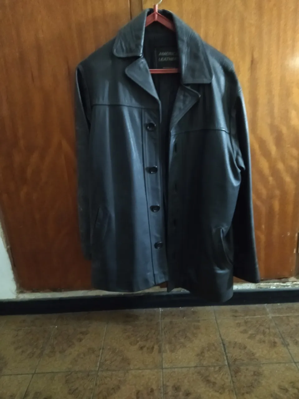 Campera de cuero negra con botones al frente y cuello solapa. Posee bolsillos laterales.