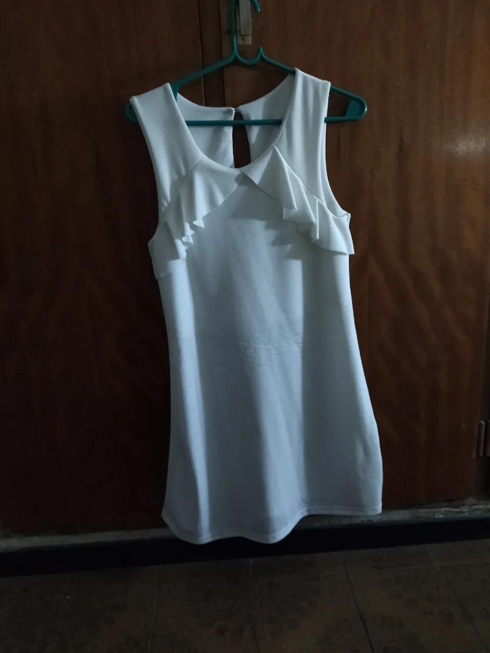 Remera blanca sin mangas con volados en el cuello. Tiene un recorte en la espalda.