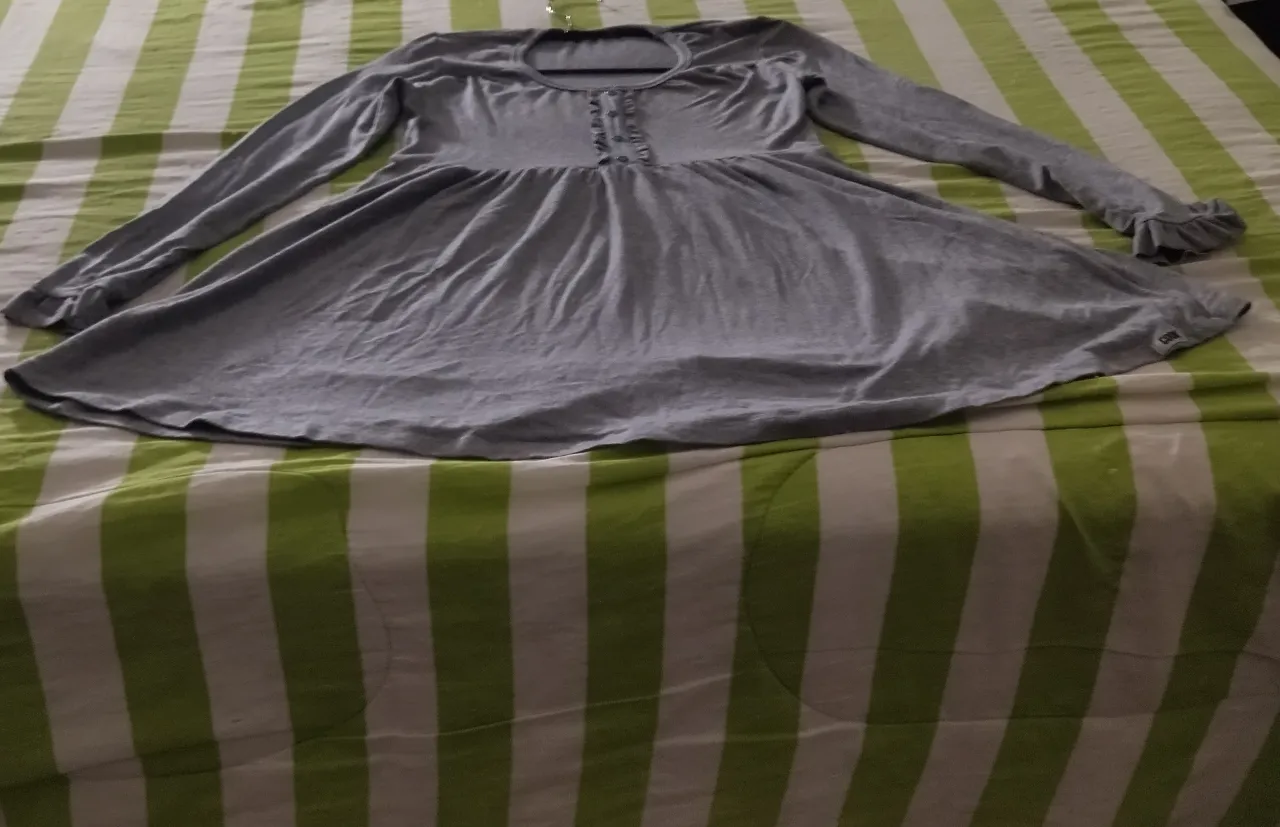 Vestido gris de manga larga con botones en el frente y volados en las mangas.