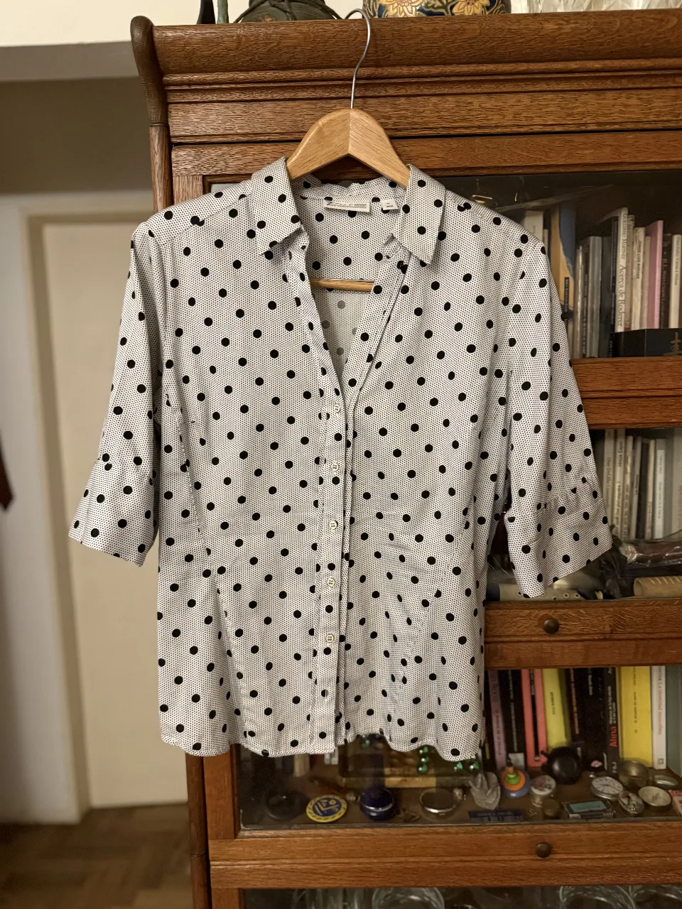 Camisa de vestir blanca con lunares negros, manga 3/4. Ideal para un look casual o de trabajo.