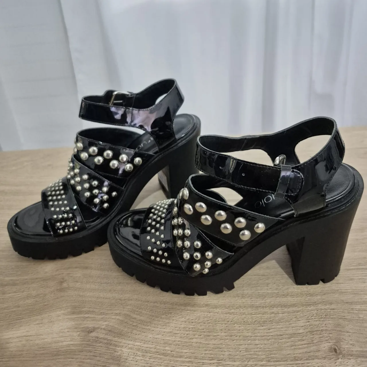 Sandalias Paruolo de cuero charol negras con plataforma y taco grueso, detalle de tachas plateadas y tiras. Hebilla regulable en el tobillo. ¡Perfectas para un look audaz y con onda! Están como nuevas!