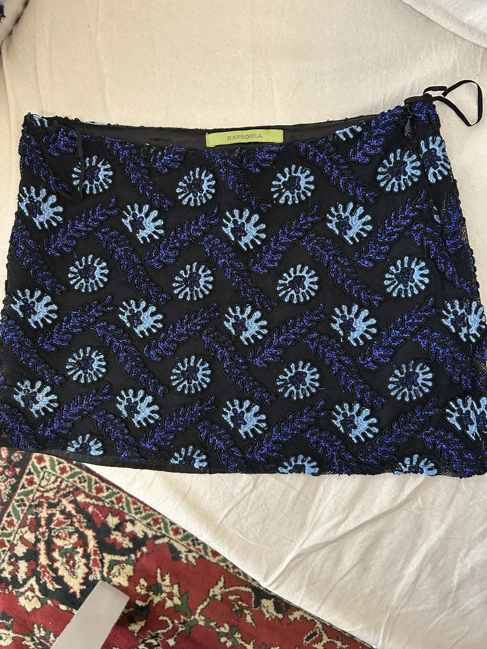 Pollera corta bordada de fiesta con bordado floral en tonos azul y celeste sobre fondo negro. Detalles de diseño y cierre lateral. talle S amplio. Impecable