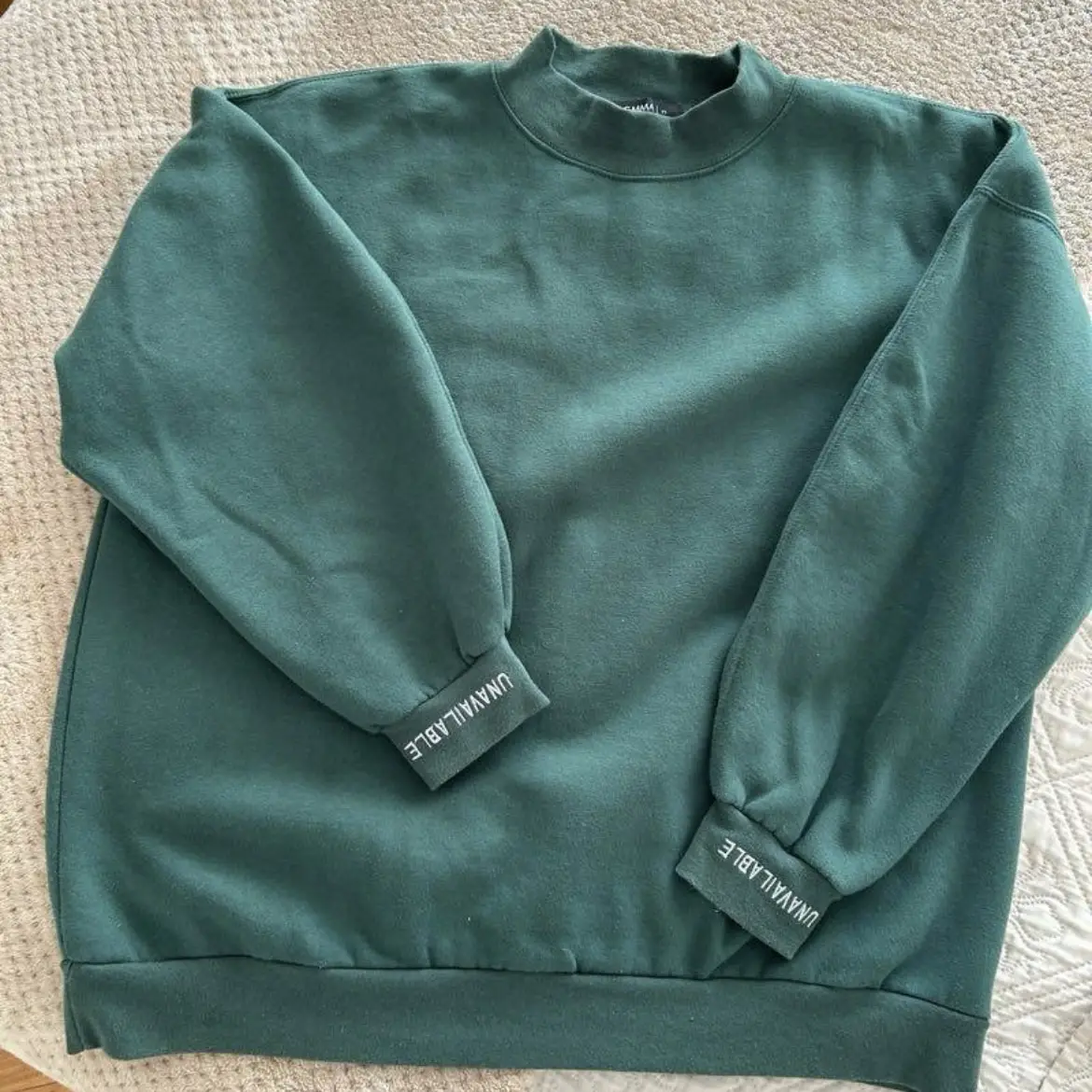 Buzo de cuello alto verde oscuro, con puños con la palabra "UNAVAILABLE" en blanco. Marca AGMMA. oversize