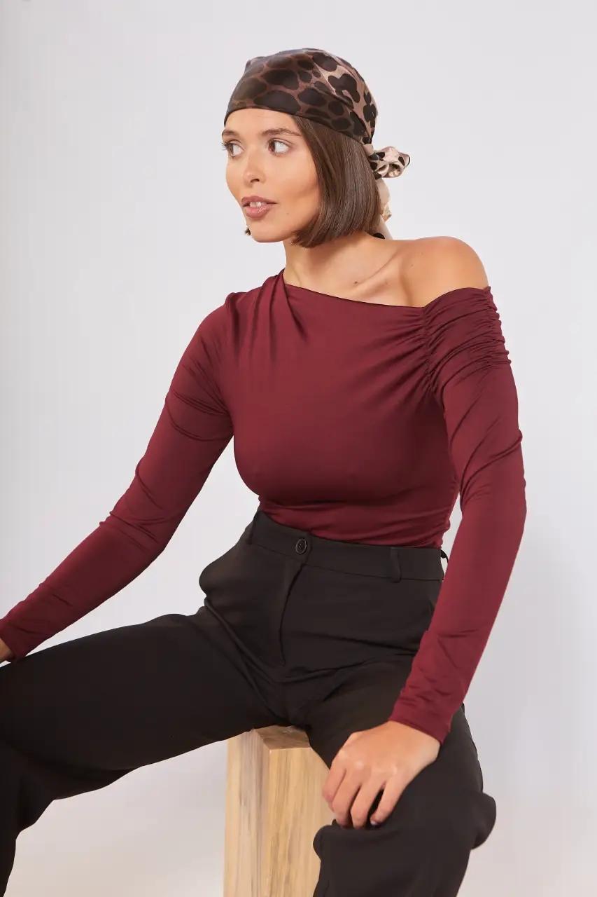 Blusa de manga larga con diseño asimétrico y fruncido en el hombro. Ideal para un look elegante y moderno.