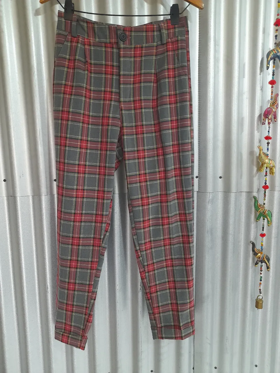 Pantalón de tela a cuadros escoceses en tonos grises, rojos y amarillos. Posee bolsillos delanteros y pinzas. un botón en la cintura. Sin uso, talle M