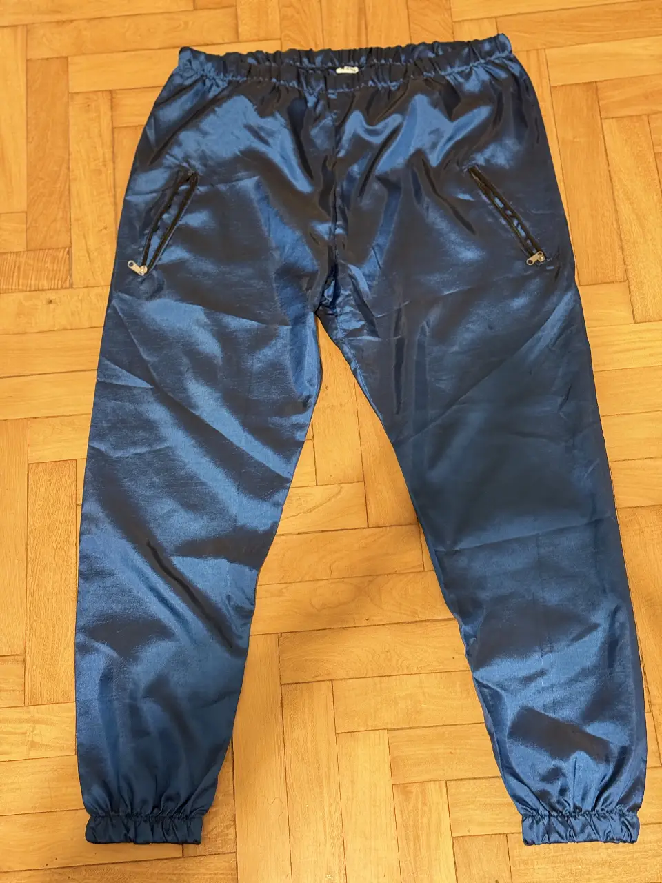 Pantalón deportivo de hombre, de tela satinada en color azul. Con cintura elastizada y bolsillos con cierre. Ideal para un look casual y cómodo.