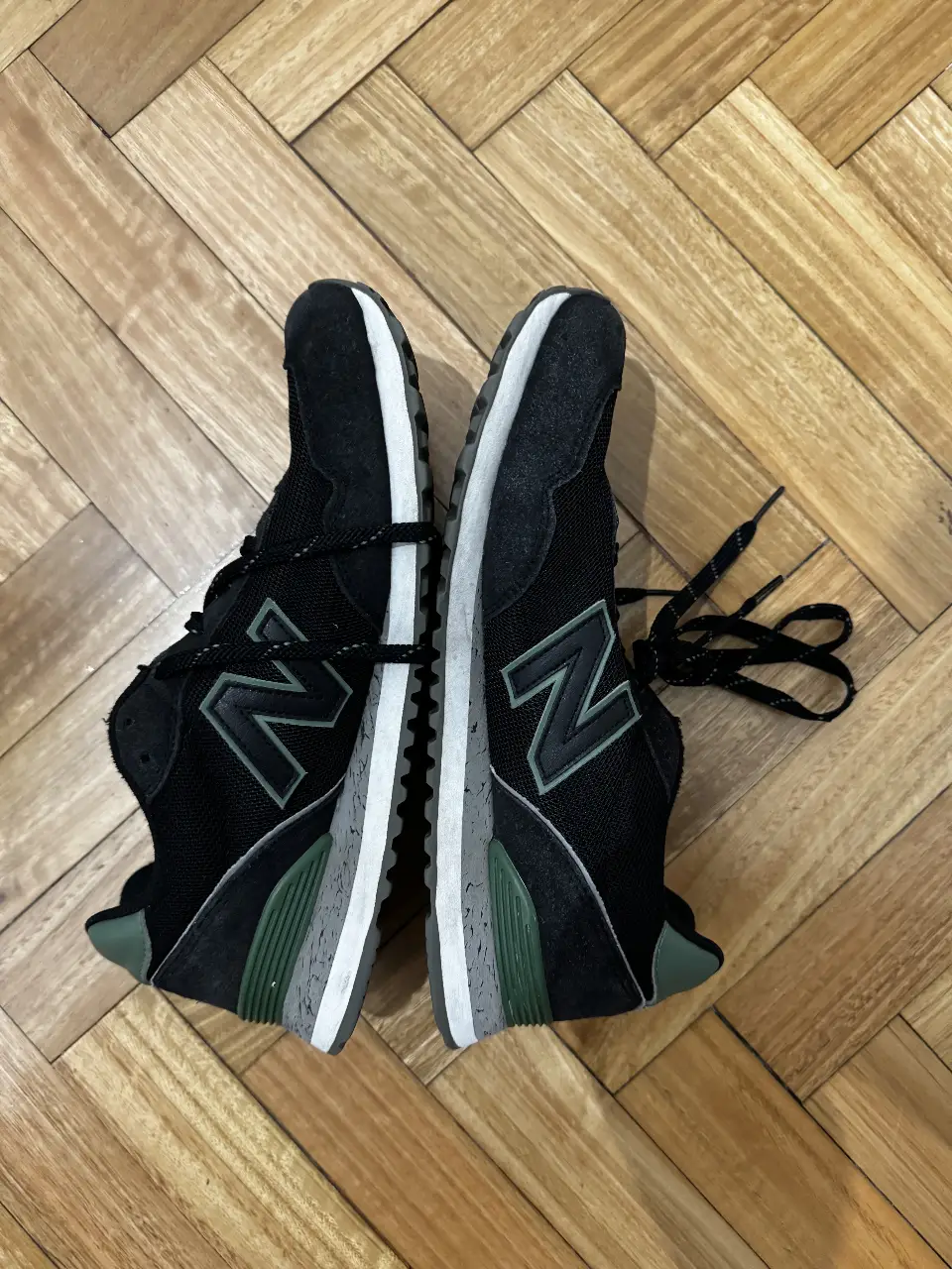 Zapatillas New Balance 515 negras con detalles en verde. Ideales para uso diario y actividades deportivas.