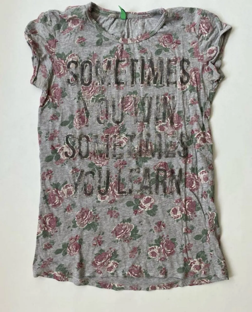 Remera de mujer gris con estampado floral y frase. Corte clásico, manga corta y cuello redondo. Ideal para un look casual y cómodo.